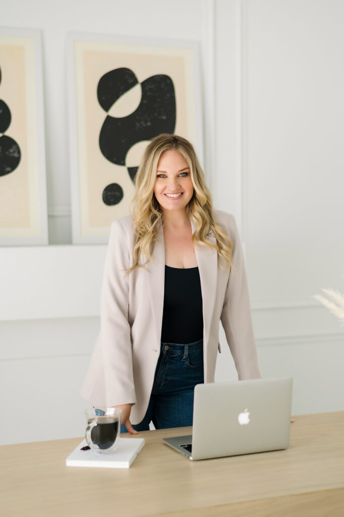 Blonde woman smiling by laptop and abstract art