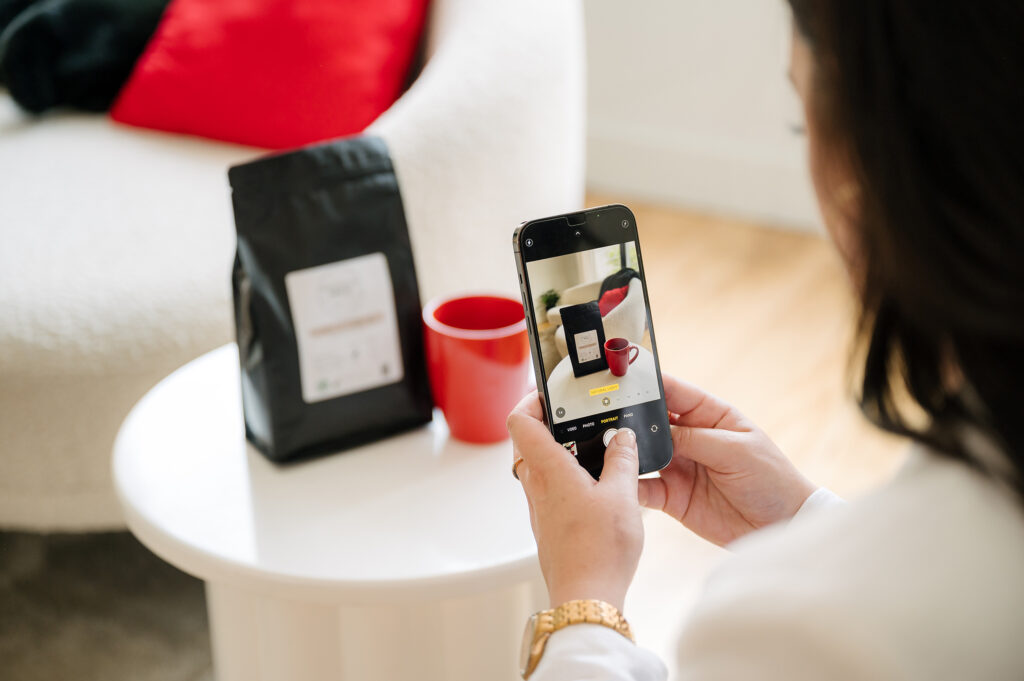 Hands holding phone taking photo of coffee and product